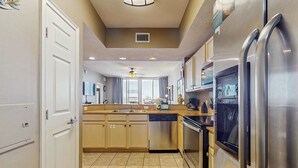 A modern kitchen with stainless steel appliances, beige cabinetry, and a central island. - Gorgeous ground floor beachfront condo, shared pool and beach access (Fort Walton Beach)