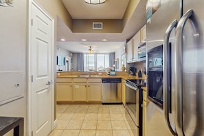 A modern kitchen with stainless steel appliances, beige cabinetry, and a central island. - Gorgeous ground floor beachfront condo, shared pool and beach access (Fort Walton Beach)