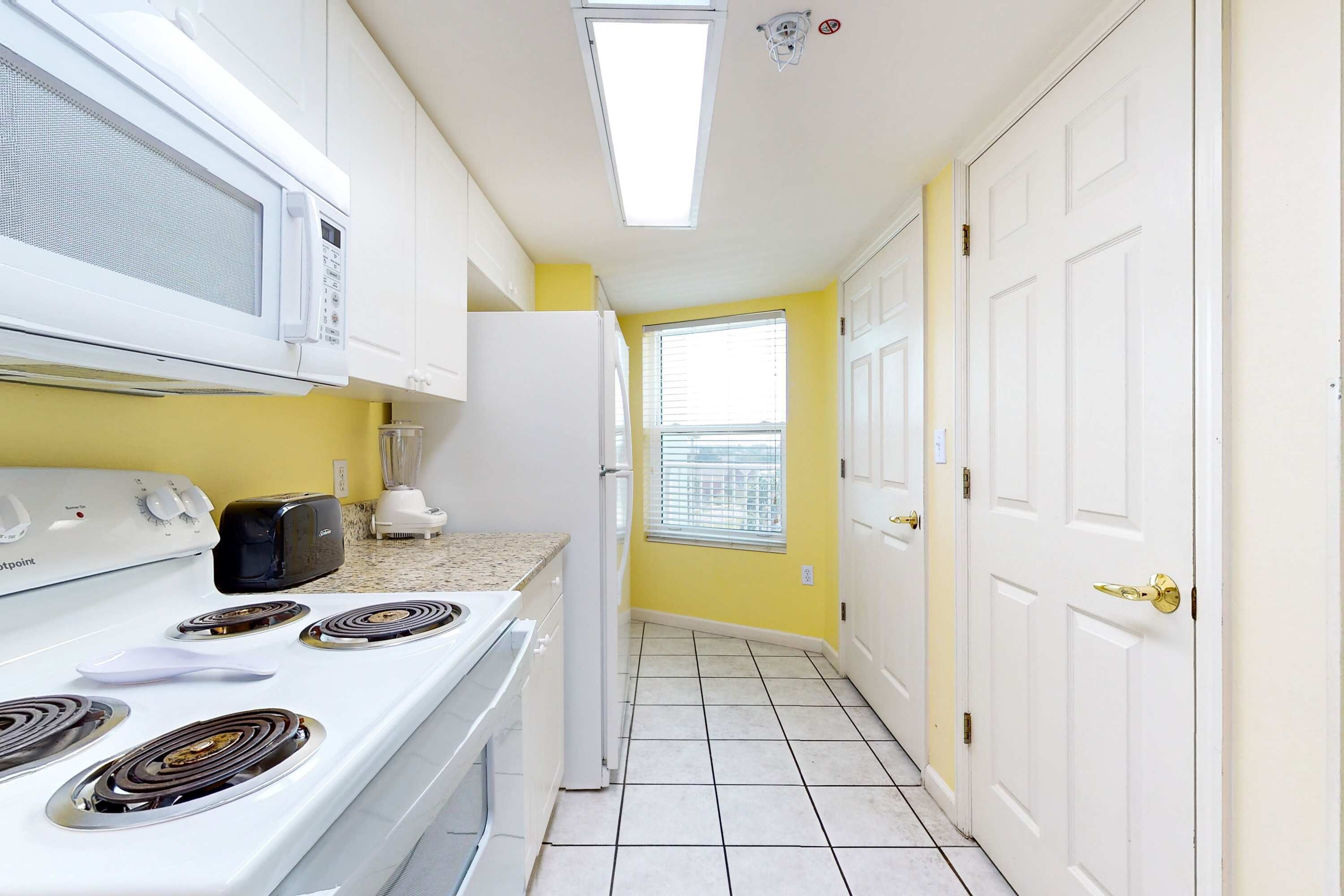 A kitchen with white appliances, a toaster, and a refrigerator.