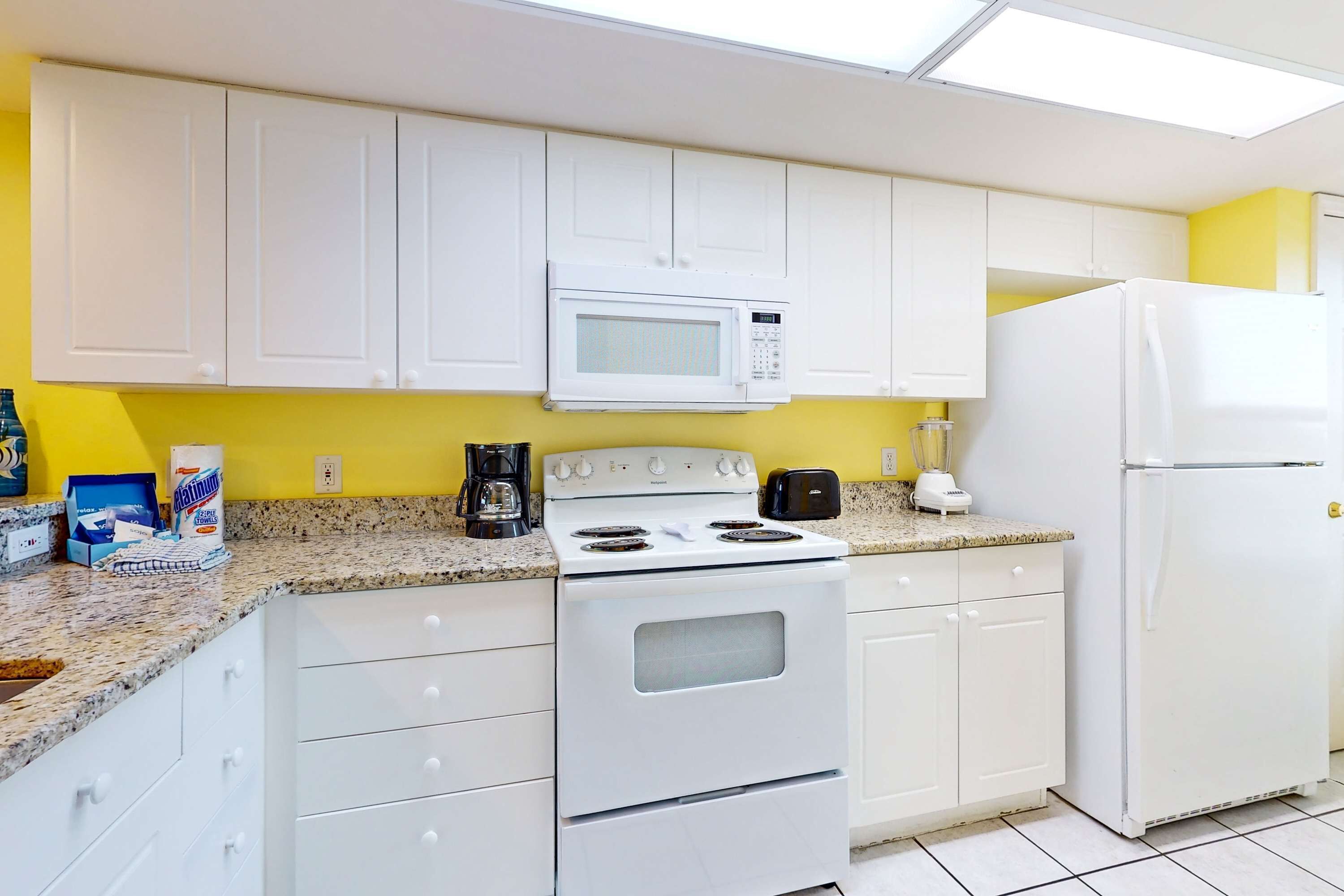 A kitchen with white cabinets, a white stove, a microwave, and a refrigerator.