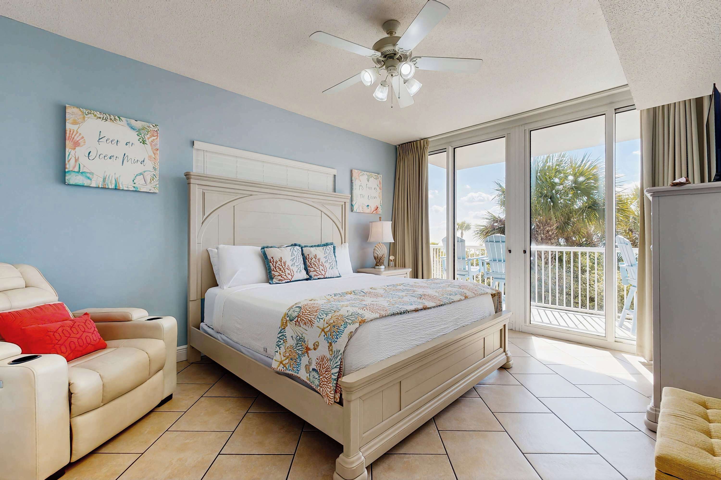 Un dormitorio con cama, una silla, ventilador de techo y vistas al exterior.