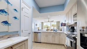 A modern kitchen with a white countertop, wooden cabinets, a dishwasher, and a ceiling fan. - Comfortable and cozy beachfront condo w shared amenities (Fort Walton Beach)