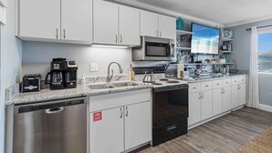Una cocina moderna con armarios blancos, electrodomésticos de acero inoxidable y lavavajillas.