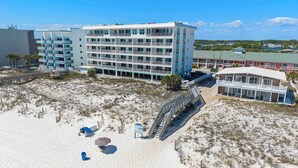 Hotel frente al mar con varios balcones, una zona de playa arenosa y una escalera que lleva a la playa.