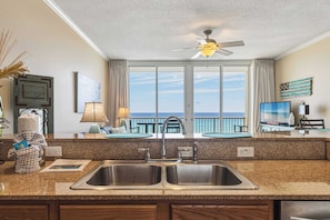 A kitchen with a large window, a ceiling fan, and a view of the ocean. - Inviting 4th Floor Condo On Okaloosa Island Gulf-Front Views Shared pool (Fort Walton Beach)