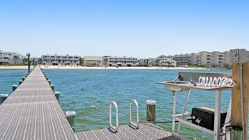A pier extending into calm water with a row of buildings in the background.