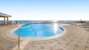 A pool with a metal ladder, surrounded by a tiled deck with lounge chairs and a covered area. - Beachfront ground-floor condo with beach & Gulf views, outdoor pool & tennis (Miramar Beach)