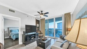 Ein modernes Wohnzimmer mit einem Flachbildfernseher, einem Deckenventilator und einem großen Fenster mit Blick auf die Stadt.