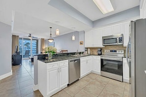 A modern kitchen with white cabinets, stainless steel appliances, and a large island. - Luxury condo with on-site pools and a convenient central location (Fort Walton Beach)