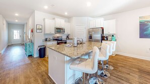 A modern kitchen with white cabinets, a granite countertop, and bar stools. - Heated community pool, themed kids room, dog friendly Beach, & Relaxing Massage (Port St. Joe)