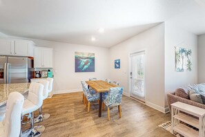 A modern kitchen with white cabinets, a stainless steel refrigerator, and a wooden dining table with chairs. - Heated community pool, themed kids room, dog friendly Beach, & Relaxing Massage (Port St. Joe)