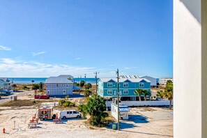 A beachfront property with a large blue house, a white van, and a small ice cream truck. - Dazzling condo near the ocean with private W/D, jetted tub, shared pool, & grill (Mexico Beach)