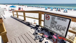 Eine Strandansicht mit einer Holzterrasse und einem Schild, das Glasbehälter verbietet.