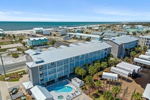 Ein Resort mit einem großen Schwimmbad, mehreren Gebäuden und Blick auf den Strand.