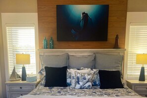 A bedroom with a bed, two nightstands, a painting above the bed, and a window with blinds. - Dog-Friendly Florida Beach House Steps from the Water in Carrabelle (Carrabelle)