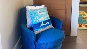 A blue armchair with a cushion that reads "Peace Comes in Waves." - Dog-Friendly Florida Beach House Steps from the Water in Carrabelle (Carrabelle)