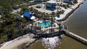 An aerial view of a coastal property with a swimming pool, beach access, and multiple houses. - Gulf-front home with infinity pool, AC, kayaks, & paddleboard - close to beach (Port St. Joe)