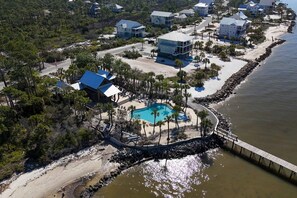 Eine Vogelperspektive eines Küsteneigentums mit Swimmingpool, Strandzugang und mehreren Häusern.