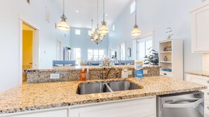 A modern kitchen with granite countertops, stainless steel appliances, and pendant lighting. - Gulf-front home with infinity pool, AC, kayaks, & paddleboard - close to beach (Port St. Joe)