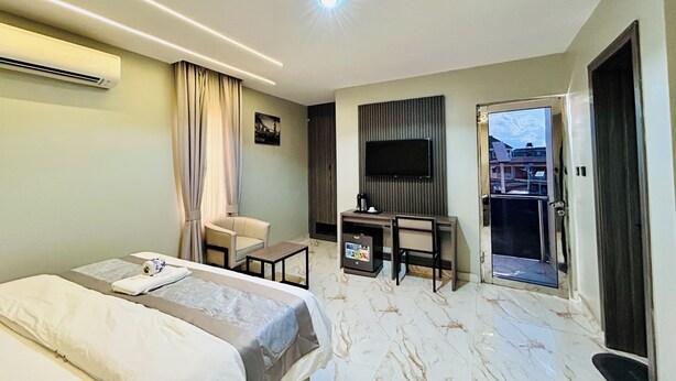 Ein modernes Hotelzimmer mit Bett, Schreibtisch, Stuhl, Fernseher und einem Balkon.