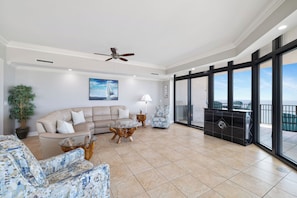 A spacious living room with a sofa, armchairs, a coffee table, a fireplace, and large windows offering a view. - The Oasis at Orange Beach 2501 by Liquid Life (Orange Beach)