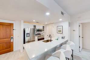 A modern kitchen with white cabinetry, stainless steel appliances, and a marble countertop. - Baytowne Wharf combo with a full kitchen plus pool, hot tub, & gym (Miramar Beach)
