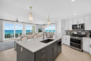 A modern kitchen with a large island, stainless steel appliances, and a view of the ocean. - Blu 507 - Luxurious gulf front condo with private balcony, shared pool & beach access (Fort Walton Beach)