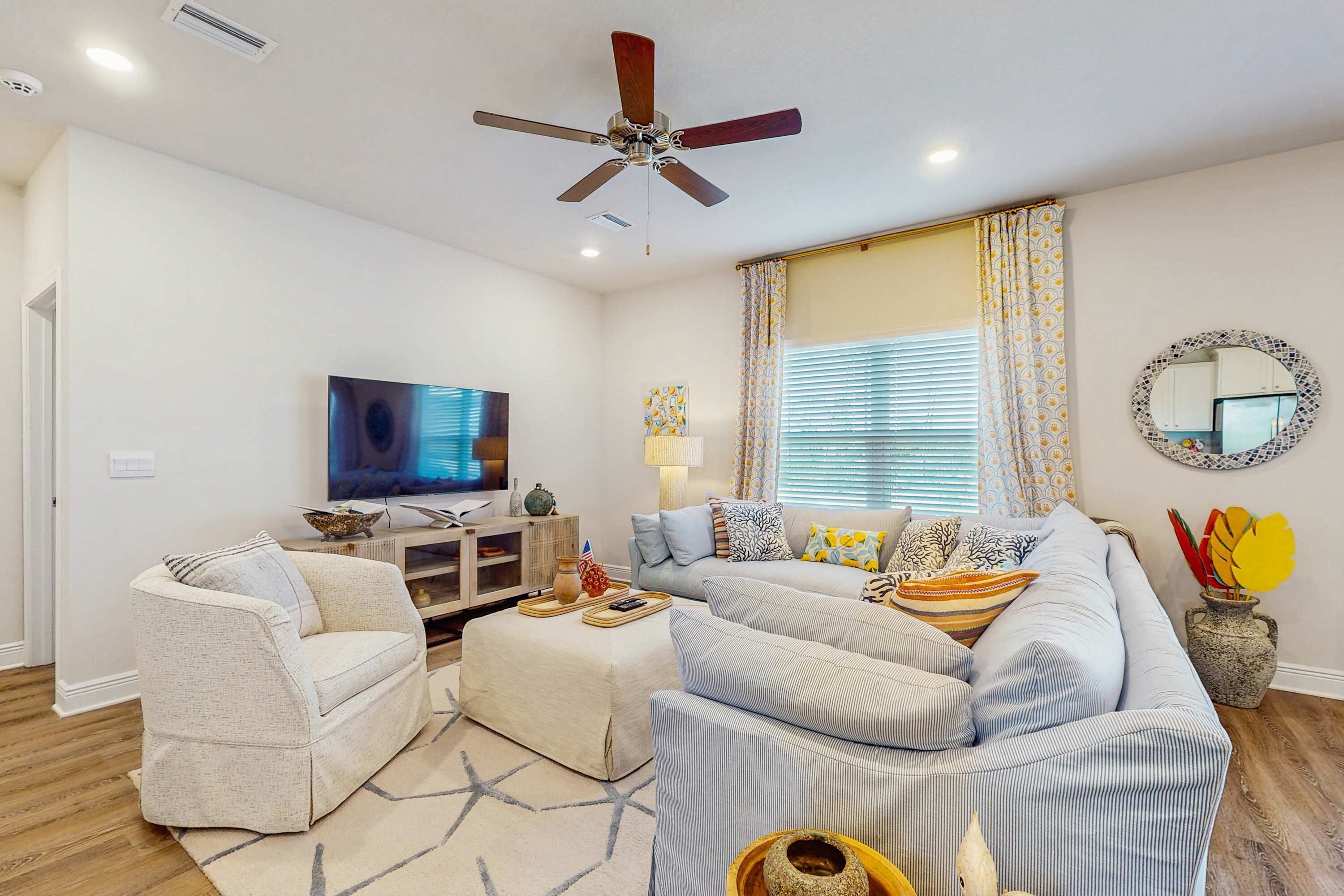 Ein Wohnzimmer mit Sofa, Sessel, Fernseher, Deckenventilator und Dekoration.