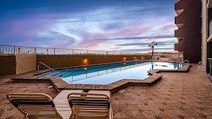 Ett poolområde på taket med fri sikt mot himlen, en pool och solstolar.