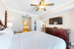 A hotel room with a large bed, a wooden dresser, a ceiling fan, and a flat-screen TV mounted on the wall. - Gulf Gem with Shared Pool, Hot Tub, Fast WiFi, Fantastic Views & Private Balcony (Fort Walton Beach)