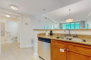 A modern kitchen with granite countertops, stainless steel appliances, and wooden cabinets. - Beachview Condo with full kitchen, shared pool and beach access (Fort Walton Beach)