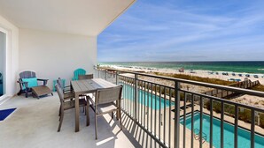 A balcony with a view of the beach and ocean, a pool, and outdoor furniture. - Blu 305 - Gulf-front condo with upgraded features - quick drive to entertainment (Fort Walton Beach)