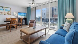 Moderni hotellihuone, jossa on parveke, ruokailutila ja suuri televisio.