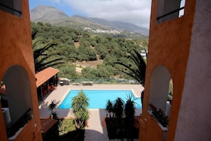 A view of a swimming pool surrounded by greenery and mountains.