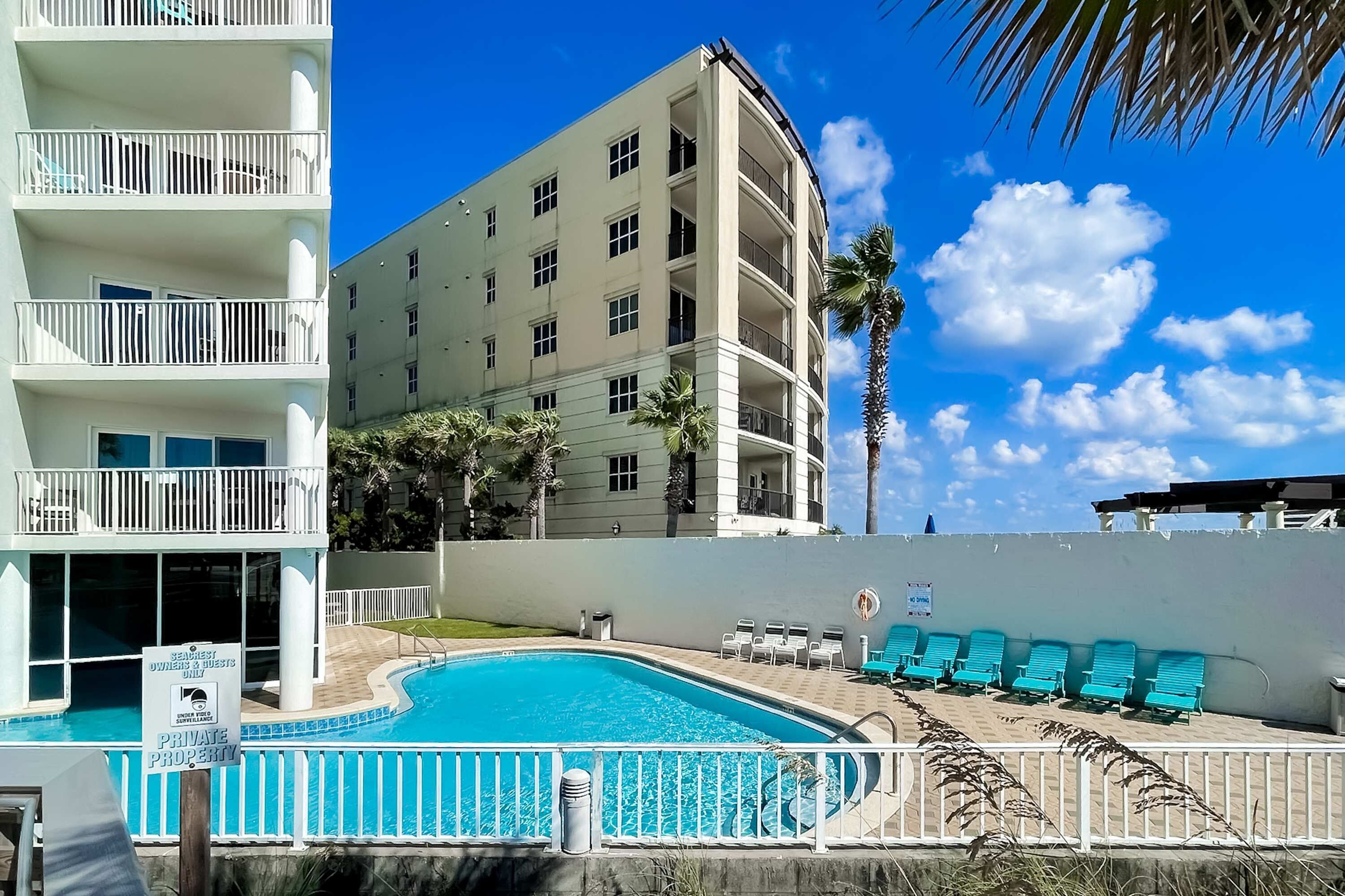 Un hôtel doté d’une piscine, d’un panneau indiquant qu’il s’agit d’une propriété privée et d’un bâtiment avec des balcons.