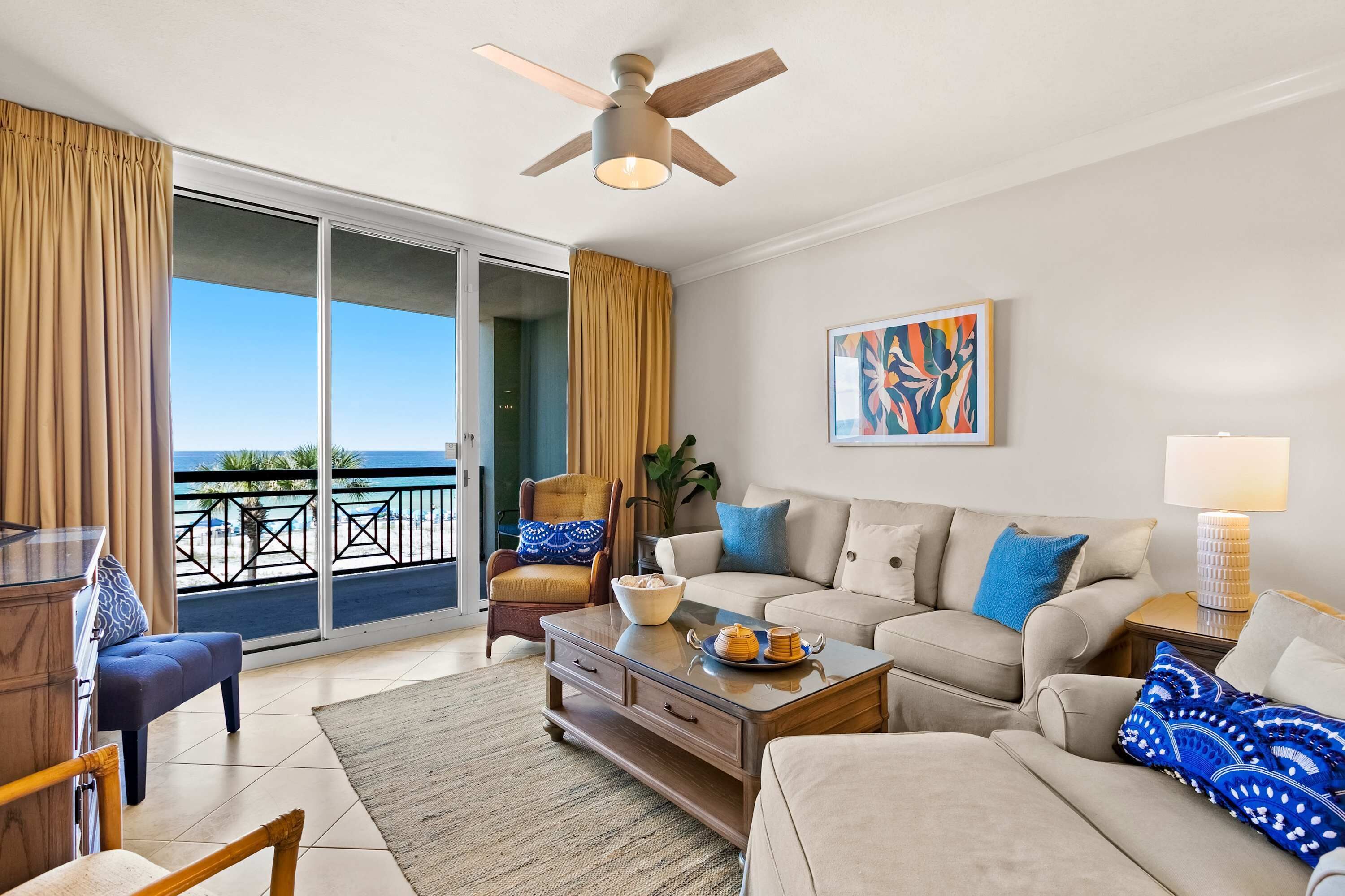 A living room with a sofa, coffee table, and a view of the ocean through large sliding glass doors.