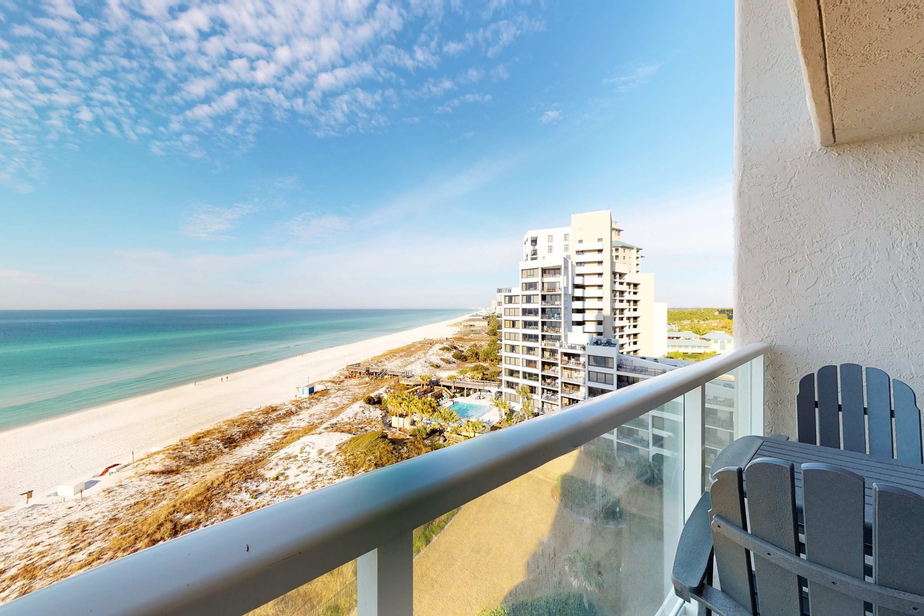 A balcony with a view of a beach and a hotel building.