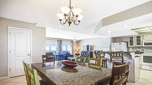 A kitchen with granite countertops, wooden chairs, a chandelier, and a dining area with a table and chairs. - Seventh floor oceanfront condo with pool, ocean view & central AC (Miramar Beach)