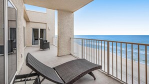 A balcony with a view of the ocean, a lounge chair, and a small table. - Seventh floor oceanfront condo with pool, ocean view & central AC (Miramar Beach)