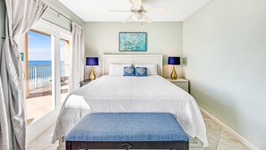 A bedroom with a bed, a ceiling fan, a painting, and a view of the ocean. - Seventh floor oceanfront condo with pool, ocean view & central AC (Miramar Beach)