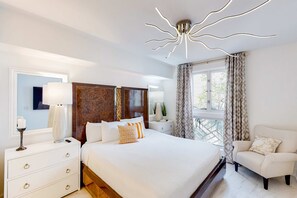 Habitación de hotel moderna con una cama grande, una mesita de noche con lámpara, una silla y un aplique de techo original.