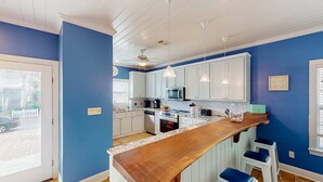 Una cocina moderna con armarios blancos, encimera de madera y paredes azules.