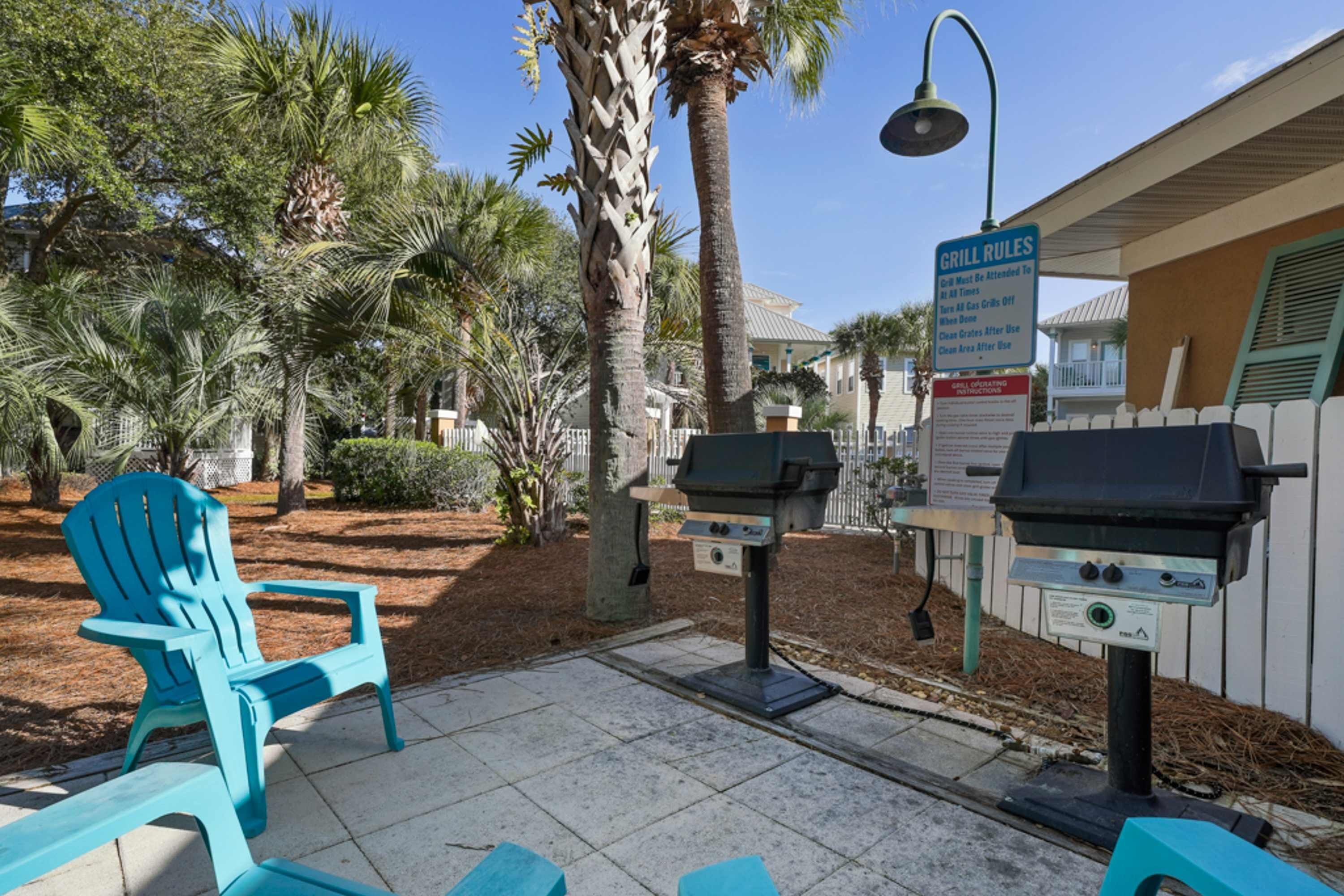 Un espace extérieur aménagé avec un barbecue, une chaise bleue et un panneau indiquant les règles d’utilisation du barbecue.