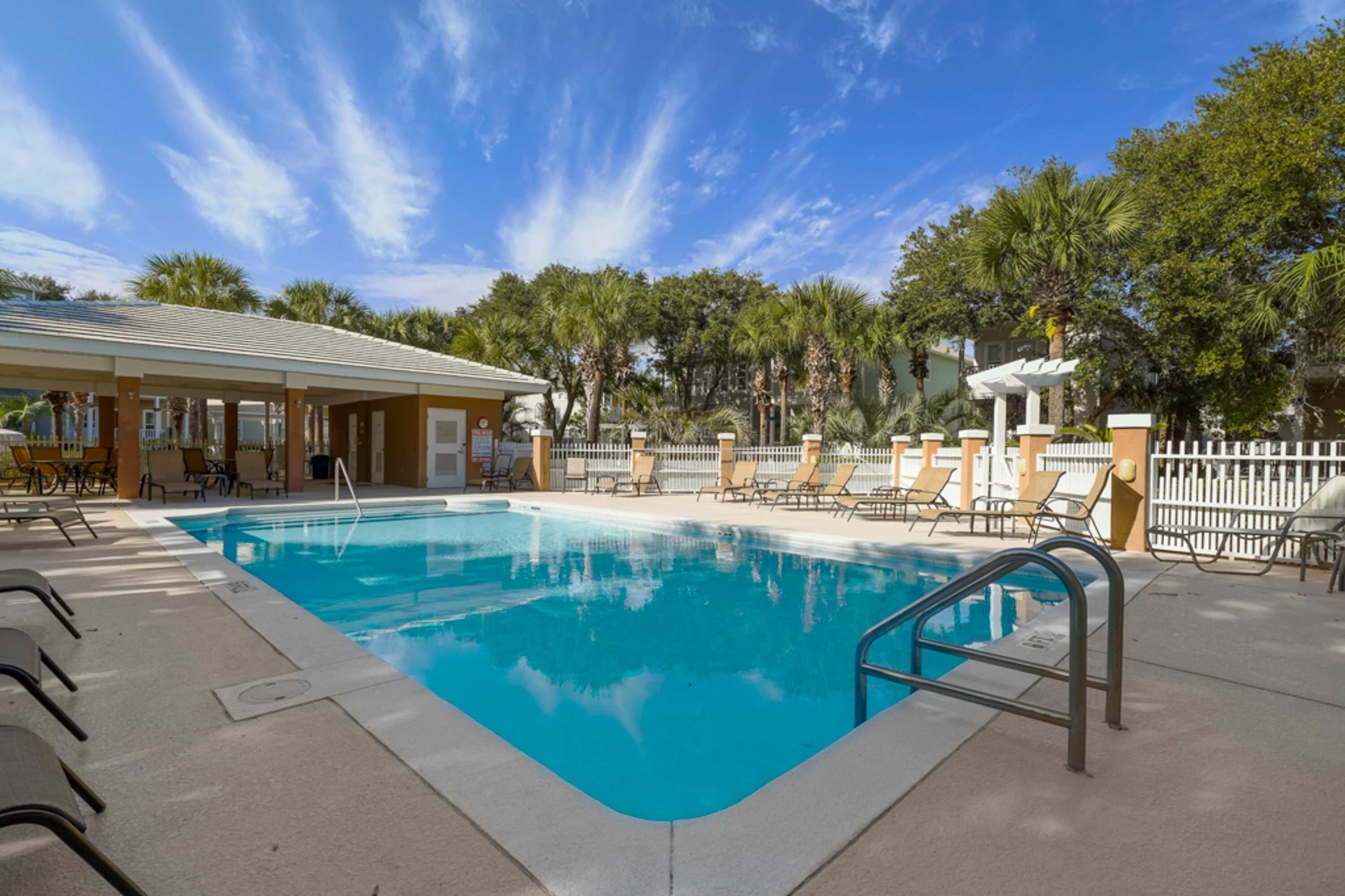 Une piscine avec des chaises longues et un espace de détente abrité.