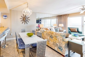 A modern living room with a dining area, a sofa set, and a balcony with a view. - Gulf-front Condo on Fifth Floor with beach Views, pool & Gym (Miramar Beach)