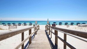A wooden boardwalk leading to a beach with umbrellas and lounge chairs. - Waterfront condo with WiFi, washer/dryer, pools, fitness room, & beach access (Pensacola Beach)