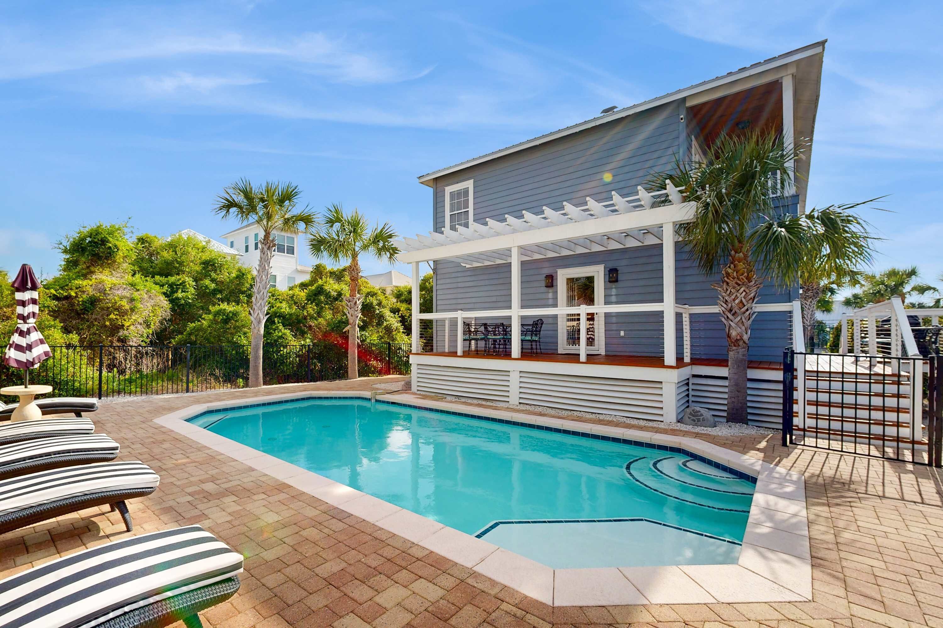 A modern pool area with a pool, lounge chairs, and a covered deck.