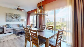 Un salon moderne avec un coin repas, de grandes fenêtres et une vue sur la ville.