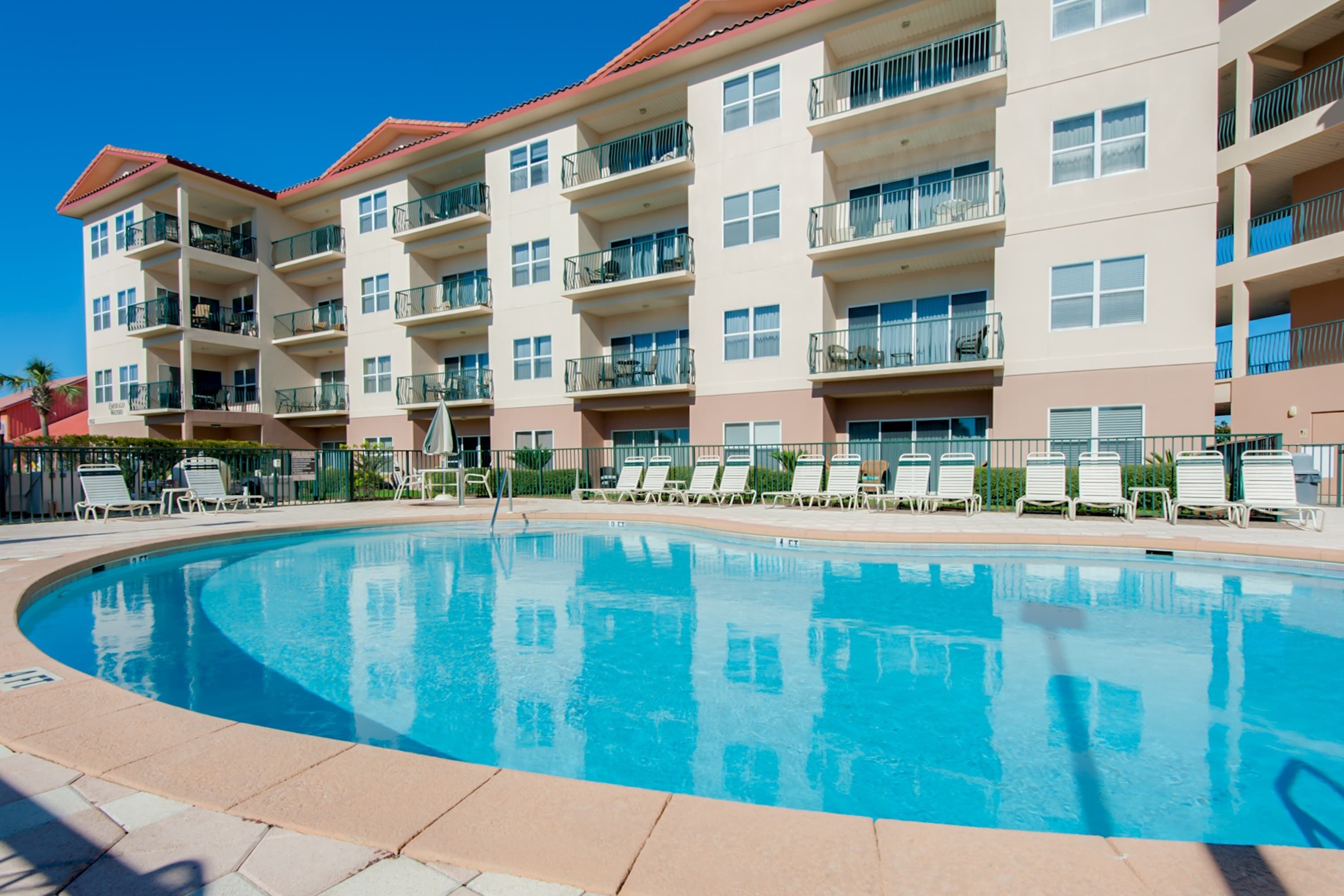 Ein mehrstöckiges Hotel mit Schwimmbad, Außenbereich und Balkonen.