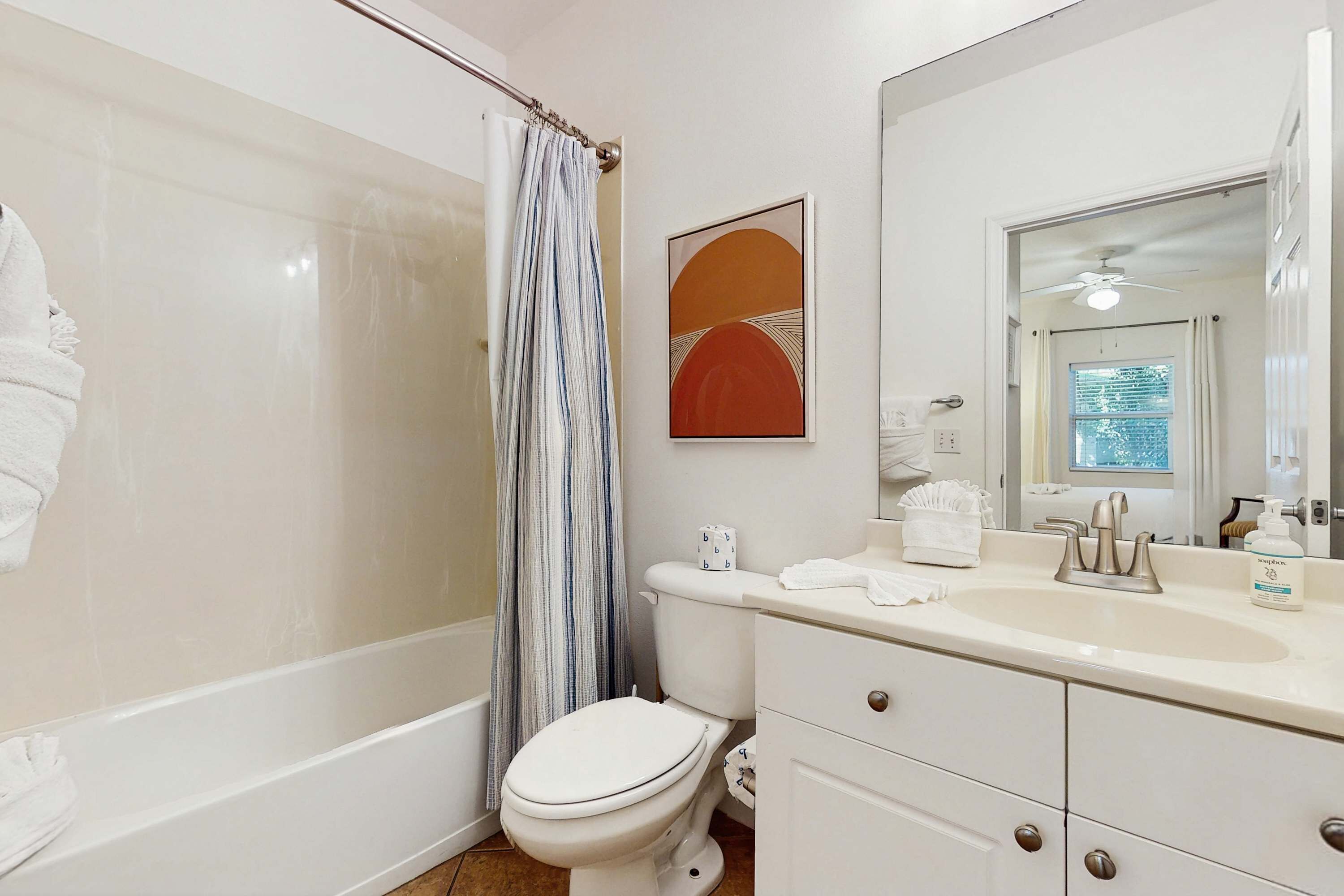 A bathroom with a bathtub, toilet, and vanity with a mirror.